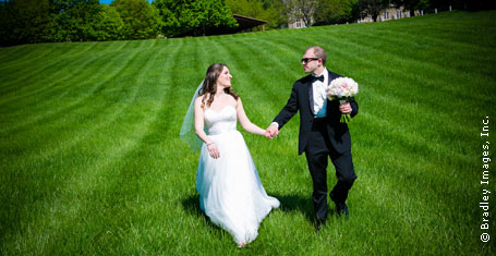 Photograph: Bride and groom holding hands on a grassy hill